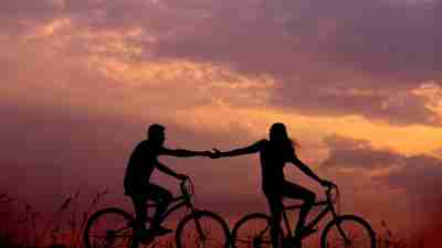 A couple hold hands while bicycling at sunset, represent an adhd couple resolving to work as a team